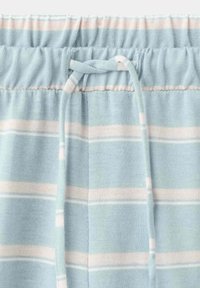 Pantalon en tissu doux rayé bleu clair et blanc, avec une ceinture élastique et un cordon noué à la taille.