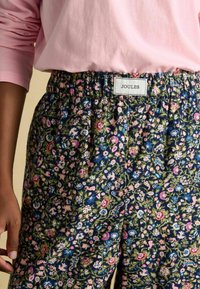 Nohavice s kvetinovým vzorom v námorníckej modrej farbe, s ružovými a zelenými kvetmi. Elastický pás so štítkom "JOULES". Mäkkučký, ľahký materiál.