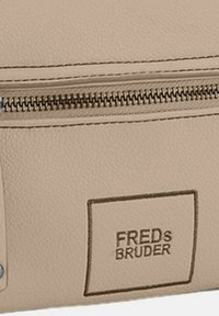 Borsa in pelle beige con superficie texture, dotata di una cerniera argentata e logo del marchio impresso, che offre un design minimalista e pulito.