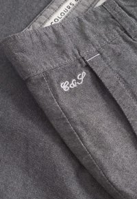 Tessuto grigio con una trama texturizzata sottile, caratterizzato da un orlo ripiegato e da un logo ricamato "C&G" sul lato, che mette in evidenza linee pulite.