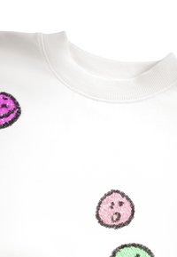 Biely sweatshirt s rebrovaným golierom, ktorý má farebné flitrové dizajny usmiatej tváre v ružovej, zelenej a fialovej farbe, s textúrovanými a lesklými detailmi.