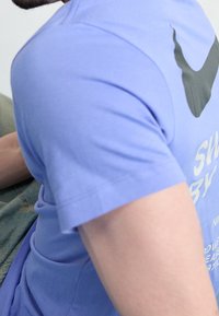 Lila kortärmad t-shirt i bomull, med en svart logotypdesign på bröstet, har en mjuk textur och en avslappnad passform.