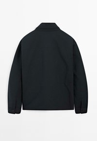 Camisetta nera a maniche lunghe con colletto, dotata di polsini con bottoni, texture liscia e design dritto. Nessun logo o fantasia visibile.