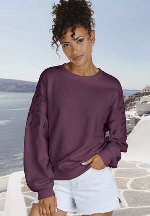 Felpa bordeaux con design intagliato complesso sulle maniche, polsini e orlo a coste, abbinata a pantaloni shorts in denim chiaro.
