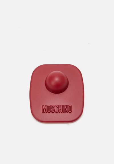 Accesoriu din silicon roșu cu o formă de vârf rotunjit, cu "MOSCHINO" embosat la bază. Textură netedă și contur pătrat.