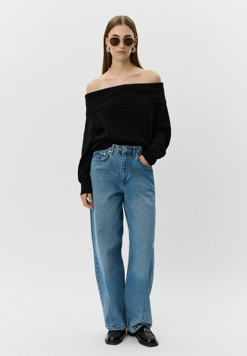 Melna off-shoulder džemperis, gaiši zili plati bikses, apaļas saulesbrilles, zelta auskari un melnas kurpes. Gluda auduma ar brīvu piegriezumu.