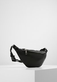 Marsupio in pelle nera con design slim e curvo, dotato di una cerniera silver e di una tracolla regolabile per un indossamento sicuro.