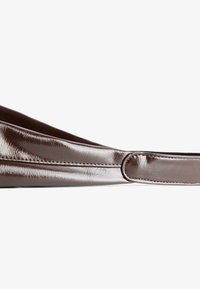 Brown, glossy bag with a sleek design and handle, presented against a white background. The focus is on its material texture and form.