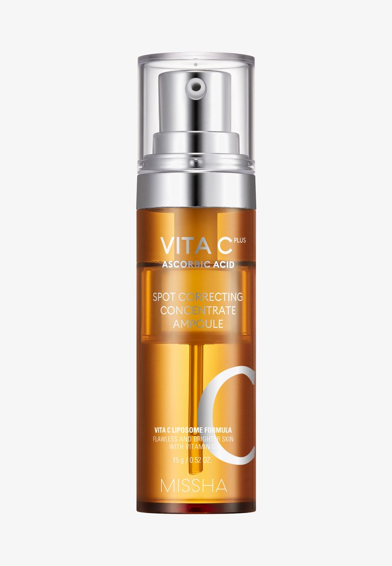 Amberglasampul med sølvfarvet pumpehoved og gennemsigtig plastikkappe. Etiket viser "VITA C PLUS" og "SPOT CORRECTING CONCENTRATE."