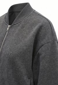 Veste zippée gris foncé avec col côtelé et tissu texturé, vue de face et d'un angle épaule droite.