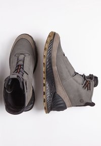 Bottes grises en matériaux suédé et synthétique, avec un design à hauteur de cheville, semelles texturées et accents orange pour les lacets.