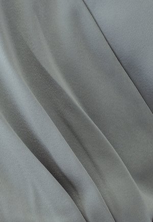 Tessuto grigio con una consistenza liscia e morbida, caratterizzato da sottili variazioni di ombreggiatura e morbide pieghe, che creano un aspetto fluido.