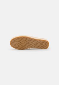 Semelle d'une chaussure en caoutchouc orange texturé, avec un motif géométrique et un profil lisse et arrondi.