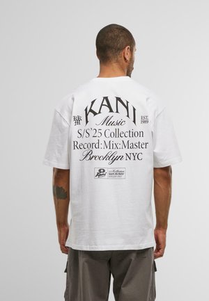 White cotton t-shirt featuring a large black text print on the back, detailing "KAN1 Music," and other graphic elements. Short sleeves.
