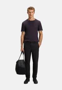 Short-sleeve dark purple T-shirt with white striped neckline, black dress pants, and a black duffel bag. Black shoes complete the outfit.