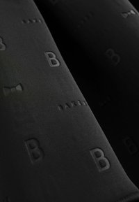 Juodas audinys su iškiliais raštais, vaizduojančiais raidę "B" ir kaklaraištį, turintis lygią tekstūrą ir matinį paviršių.