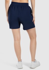 Pantalones cortos deportivos en azul marino, confeccionados con un tejido suave y elástico, que presentan una cinturilla ancha y un diseño de largo hasta mitad del muslo.