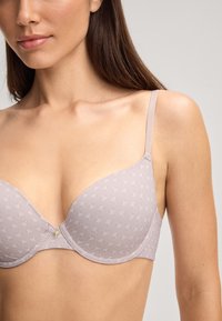 Mauve gewatteerde beha met een gladde afwerking, voorzien van een subtiel patroon en dunne verstelbare bandjes, met een kleine decoratieve accent in het midden.