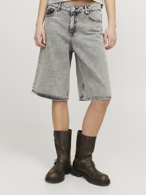 Black and white denim Bermuda shorts with a loose fit, features frayed hems and a high waist. Paired with dark brown leather ankle boots.