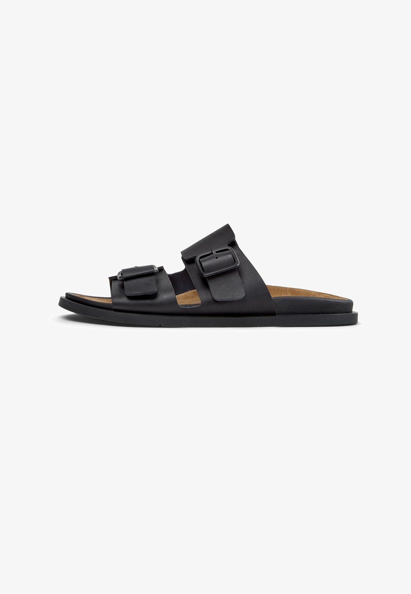 Sort læder-slide sandal med to justerbare spænderemme, kork-indersål, minimalistisk design og flad gummisål.