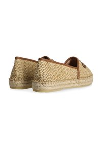 Zapatos de paja trenzada en un color tostado natural, con una suela de yute trenzada y detalles en cuero marrón en la abertura y el talón.