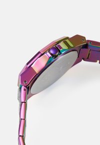 Lila metallische Uhr mit einem achteckigen Gehäuse, verknüpftem Armband und einer runden Krone. Verfügt über eine reflektierende Oberfläche und eine glatte, flache Rückseite.