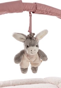 Plush gray and white donkey toy wearing light pink overalls hanging from a pink fabric arch above a pale pink polka dot cushion.