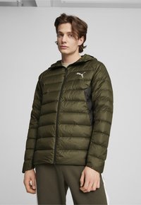 Oliven grøn pufferjakke med hætte, med et sort sidepanel og et hvidt logo. Struktureret stof med quiltet design og lynlås foran.