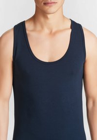 Canottiera navy in morbido misto cotone. Presenta un collo rotondo e spalline sottili. Tessuto liscio con una vestibilità aderente.