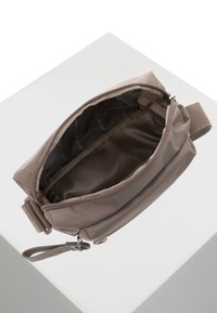 Piccola borsa rettangolare realizzata in tessuto taupe testurizzato con chiusura a zip. L'interno è foderato in tessuto scuro e presenta un piccolo anello per le chiavi.