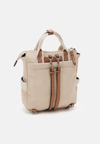 Bolso tote de lona beige con correas de cuero marrón, broches de metal plateado, dos asas, parte superior con cremallera y bolsillos laterales.