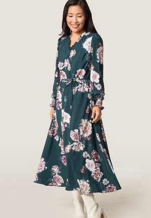 Robe florale en bleu sarcelle foncé avec des manches longues, un col froncé, une taille élastique, arborant de grands motifs de roses en blanc et en rose.