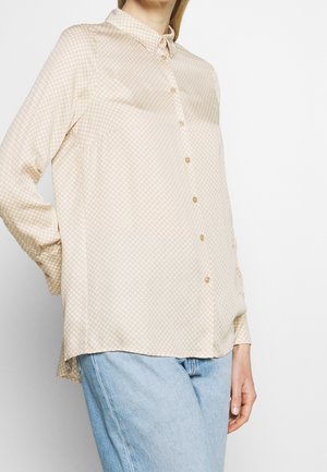 Beige skjorta med knappar och ett litet rutmönster, långa ärmar och krage. Har en avslappnad passform och en lätt, slät tygkvalitet.