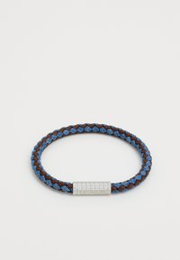 Vævet armbånd med blå og brune fibre, med en sølvmetal lås, der viser brandnavnet, GUESS. Cirkulær form med tekstureret overflade.