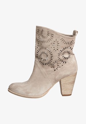 Beiger Wildleder-Stiefelette mit ausgeschnittenem Blumenmuster am Schaft, schmal zulaufendem Absatz und strukturiertem, gestapeltem Absatzboden.