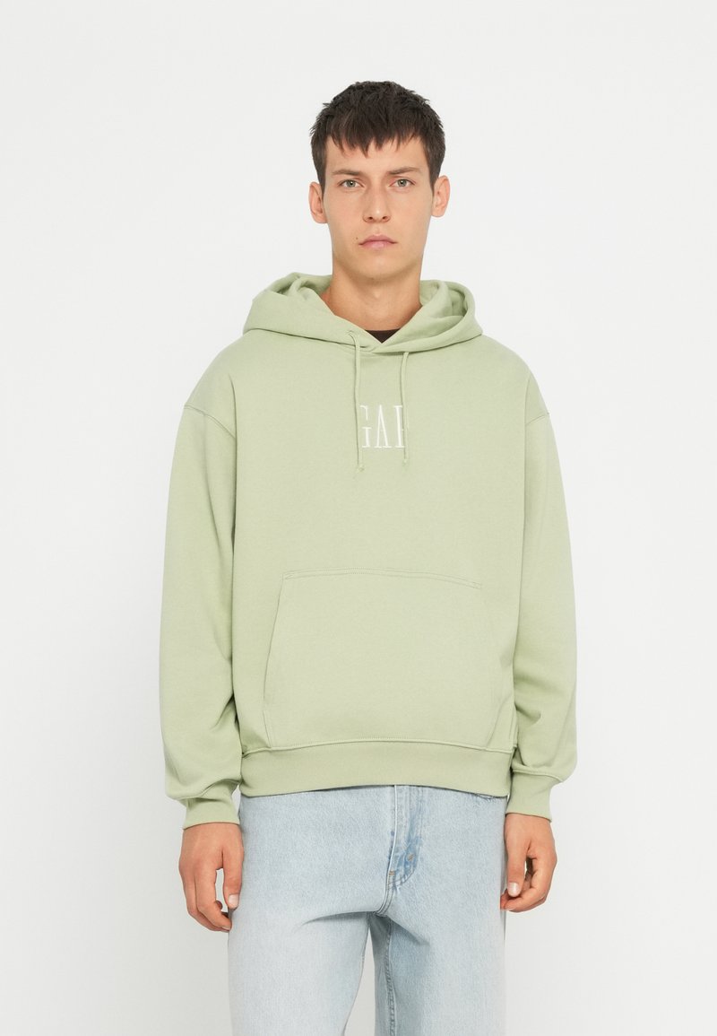 Felpa verde chiaro con tasca a marsupio, cappuccio con cordino e dettagli con logo. Tessuto morbido con una vestibilità comoda, abbinata a jeans in denim chiaro.