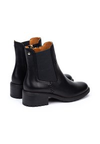 Bottines en cuir noir avec panneaux latéraux élastiques et un talon épais. Présente une finition lisse et un doublure intérieure marron. Accents en métal argenté.