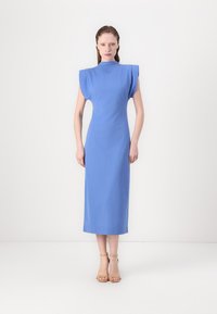 Blue midi dress with structured, short sleeves and high neck. Smooth, textured fabric falls straight to the ankles. Sandals complement the look.