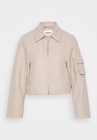 Beige kort jacka med krage, frontdragkedja och två fickor med dragkedja. Tyget har en mjuk textur och pryds av guldiga detaljer.