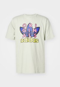 Světle zelené bavlněné tričko s výrazným růžovým a žlutým nápisem "ORIGINALS" a modrým třemi pruhy a logem trojlístku vpředu.