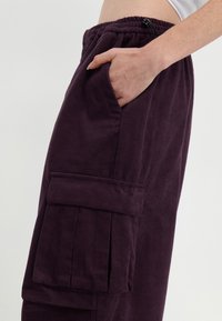 Lila kordflamsbyxor med avslappnad passform, med sidofickor och en cargoficka på låret. Elastisk midja med dragsko.