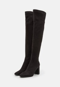 Bottes noires montantes en daim, dotées d'un bout pointu et d'un talon chunky haut, avec un design épuré et des détails de couture minimaux.