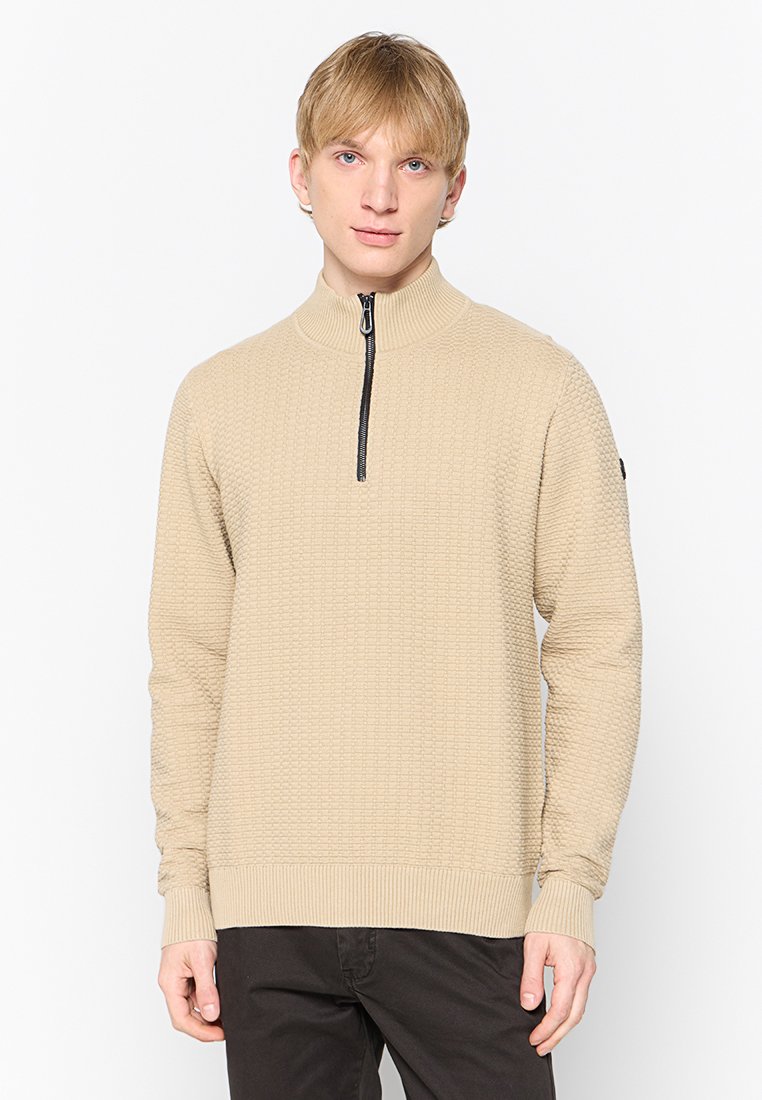Beige Viertelreißverschluss-Pullover mit strukturiertem Muster, gerippten Bündchen und Saum, ausgestattet mit einem schwarzen Reißverschluss und einem Logo-Patch am Ärmel.