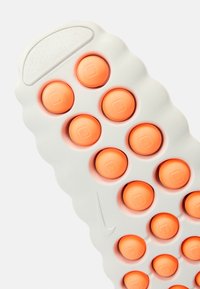 Σόλα παπουτσιού Nike με υφασμένη λευκή βάση που διαθέτει ανυψωμένα πορτοκαλί κυκλικά σχέδια και λείο πάνω μέρος με διάτρητη περιοχή.