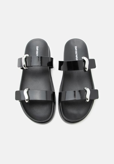 Ζευγάρι μαύρα σανδάλια slides με δύο γυαλιστερές λουριά, κάθε ένα με ασημένιες αγκράφες και μαλακές υποδοχές πέλματος σε λευκό φόντο.