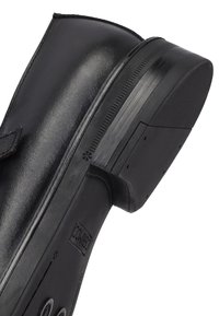 Schwarze Lederknöchelstiefel mit geschwungener Form, Gummisohle und kleinem Absatz. Verfügt über einen Riemen und stikstoffe Details entlang des Schafts.