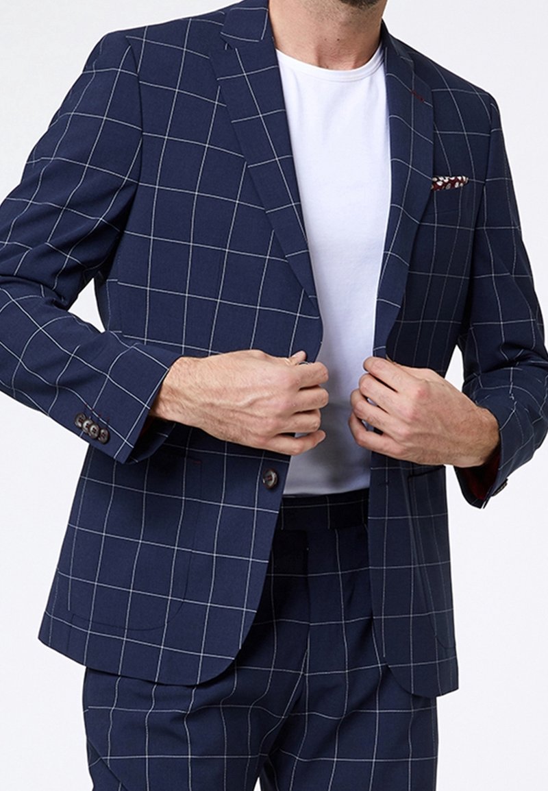 Navy blue blazer with a grid pattern, single-breasted design, notch lapels, and button accents. Worn over a white shirt.