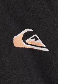 Black fabric with a prominent cracked logo featuring a stylized wave in cream and peach tones, adding texture to the design.