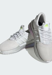 Białe sportowe sneakersy z teksturowaną siateczkową cholewką, odblaskowymi akcentami i wyściełanym kołnierzem. Posiadają gradientową podeszwę i sznurówki.