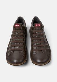 Zapatillas de cuero marrón con una textura suave, con punta redondeada, seis ojetes y el logotipo rojo de "Camper" en la lengüeta.